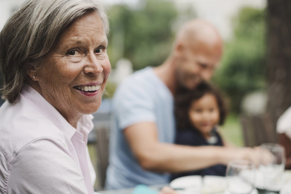 Eldre dame med barn og barnebarn i bakgrunnen