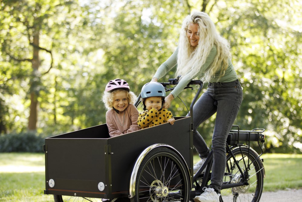 Dame sykler med to barn