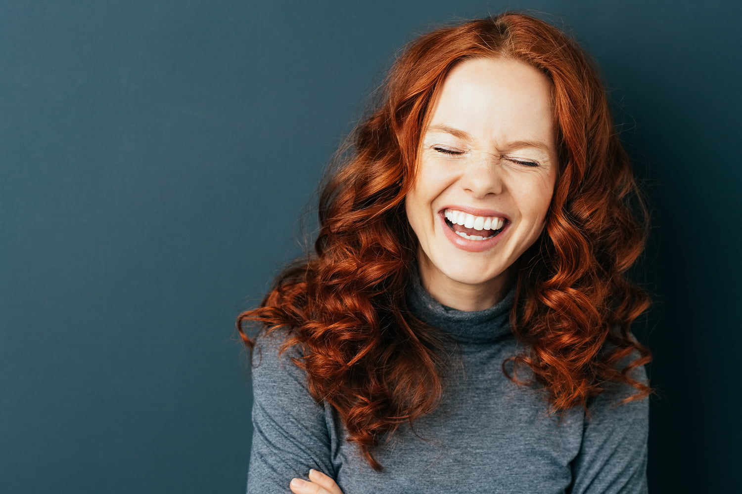 En jente smiler bredt med lukkede øyne