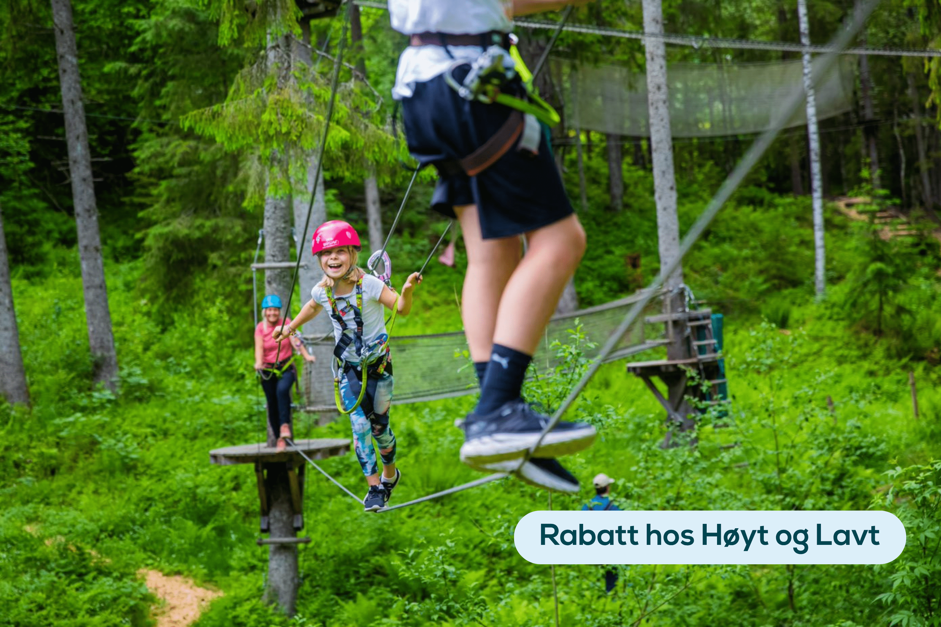 Jente på line i klatreparken. Med hjelp og sikkerhetssele.