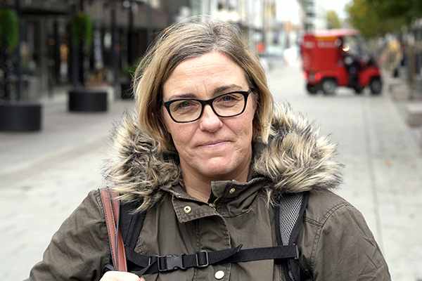 Kvinne med oppgitt uttrykk i ansiktet, varm jakke og veske over skulderen