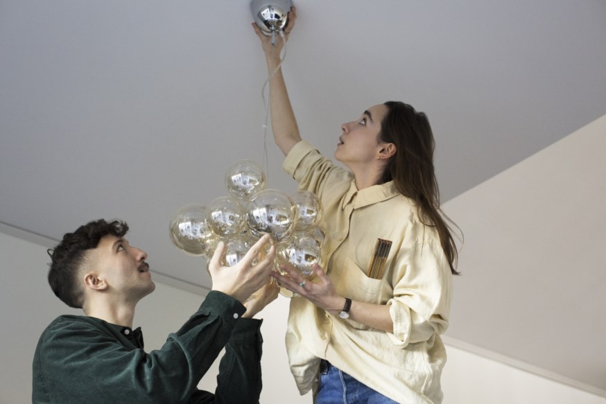 Et ungt par henger opp lampe i sin nye leilighet